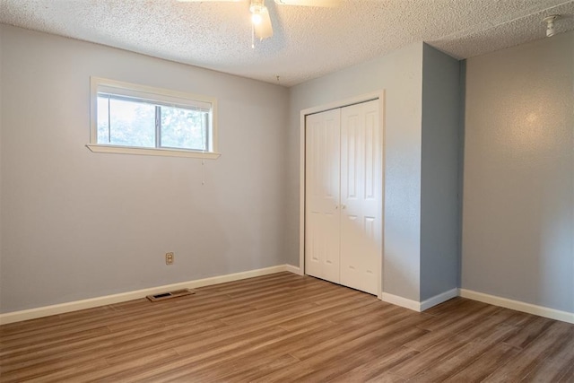 515 W Tennessee Ave, Pauls Valley, OK 73075 - unfurnished bedroom featuring a closet, light wood finished floors, a textured ceiling, baseboards, and ceiling fan