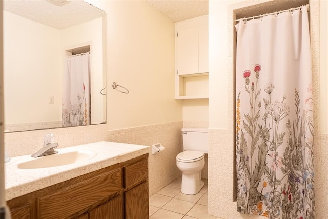 515 W Tennessee Ave, Pauls Valley, OK 73075 - full bath featuring vanity, toilet, a textured ceiling, a wainscoted wall, and tile patterned floors