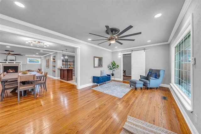2736 Pembroke Ter, Oklahoma City, OK 73116 - living room featuring a barn door, light wood finished floors, ceiling fan, and a lit fireplace