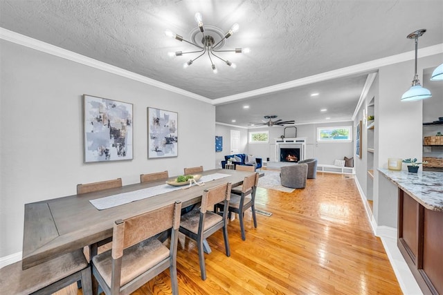2736 Pembroke Ter, Oklahoma City, OK 73116 - dining room with ornamental molding, light wood-type flooring, a lit fireplace, a chandelier, and a textured ceiling