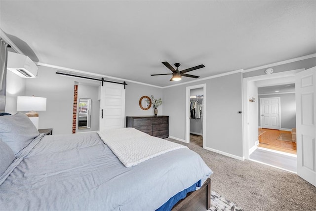 2736 Pembroke Ter, Oklahoma City, OK 73116 - carpeted bedroom featuring a barn door, a wall unit AC, a walk in closet, crown molding, and baseboards