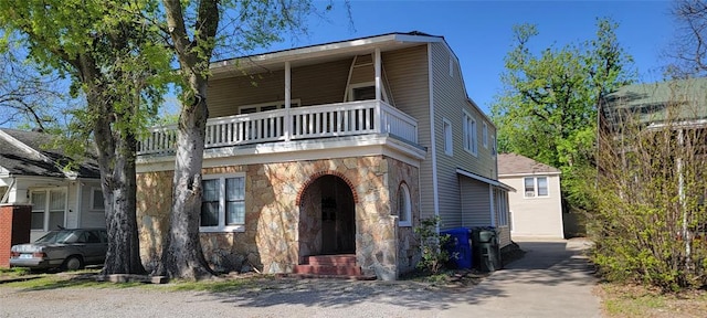view of front of house featuring stone siding and a balcony