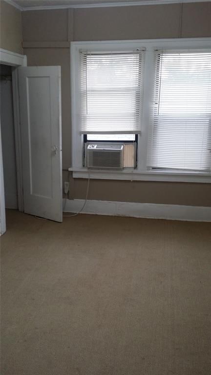 unfurnished room with cooling unit, light colored carpet, and ornamental molding