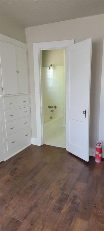 unfurnished bedroom with ensuite bathroom and dark wood finished floors