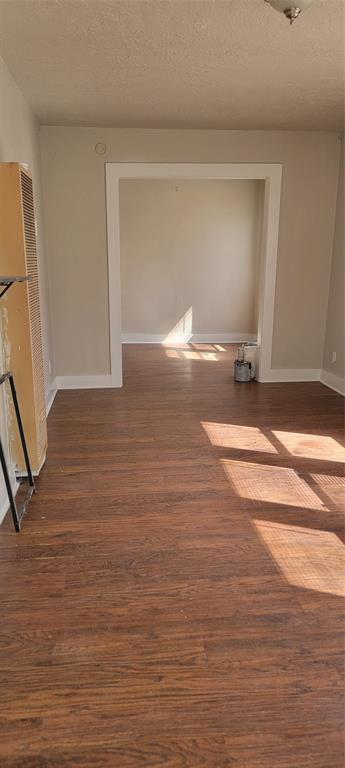 corridor featuring a textured ceiling, baseboards, and dark wood finished floors