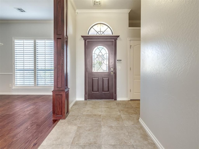 foyer entrance featuring visible vents, crown molding, and baseboards