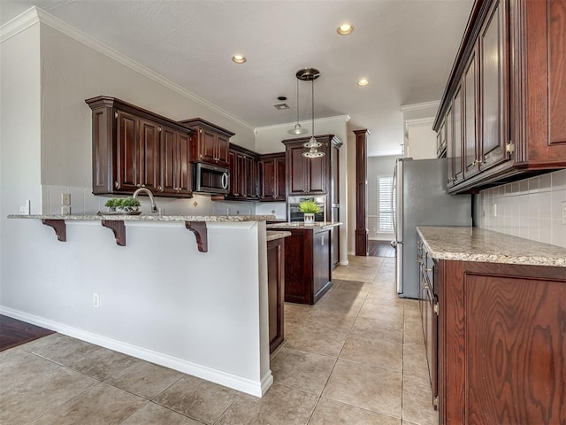 kitchen featuring a peninsula, a kitchen bar, appliances with stainless steel finishes, and light tile patterned floors
