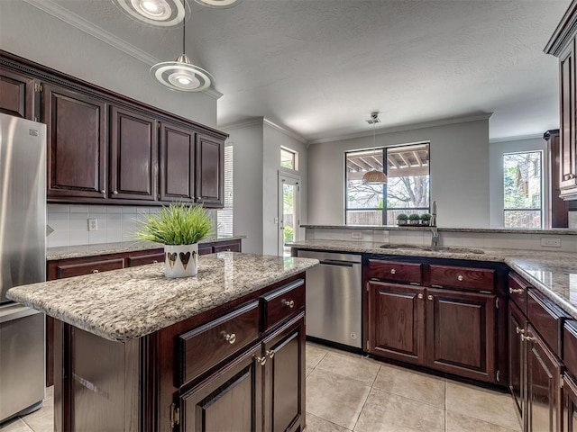 kitchen featuring stainless steel appliances, ornamental molding, a sink, decorative light fixtures, and a kitchen island