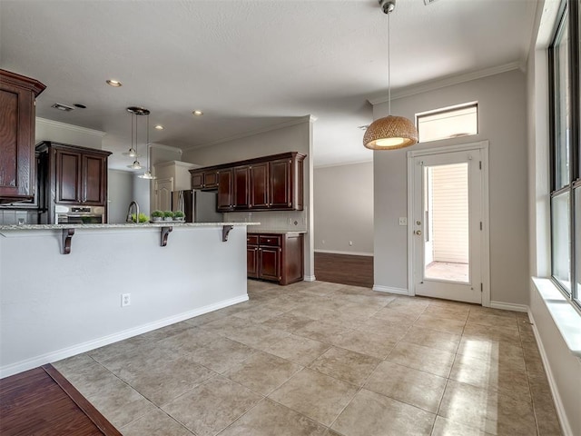 kitchen featuring crown molding, a kitchen bar, a peninsula, appliances with stainless steel finishes, and decorative light fixtures