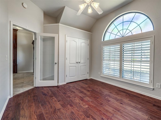 unfurnished bedroom featuring vaulted ceiling, baseboards, wood finished floors, a closet, and ceiling fan