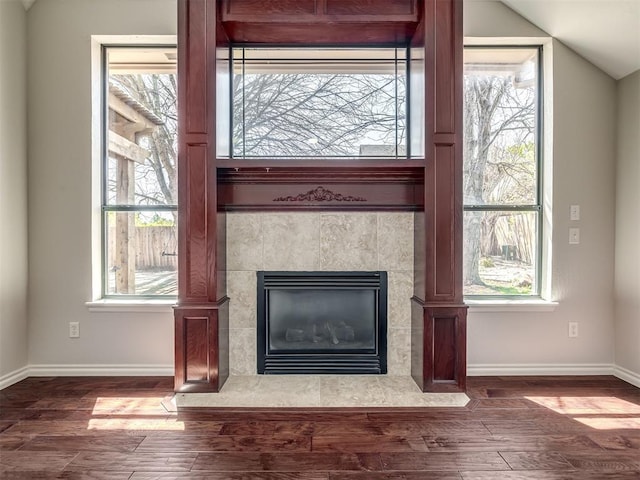 details featuring baseboards, a tile fireplace, and wood finished floors