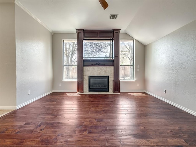 unfurnished living room with hardwood / wood-style floors, ceiling fan, a textured wall, a tile fireplace, and visible vents