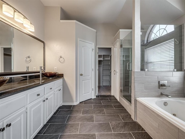 bathroom with a shower stall, a tub with jets, a spacious closet, vanity, and baseboards