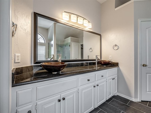full bathroom featuring a textured wall, tile patterned flooring, a sink, and a stall shower