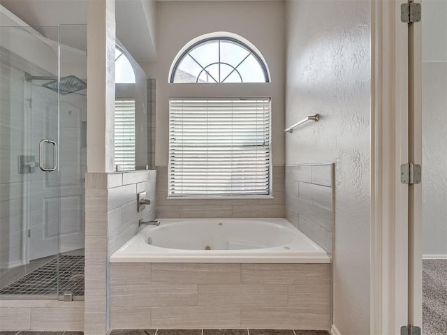 full bath featuring a textured wall, a whirlpool tub, and a stall shower