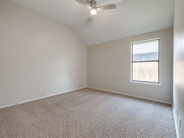 carpeted spare room with vaulted ceiling, baseboards, and ceiling fan