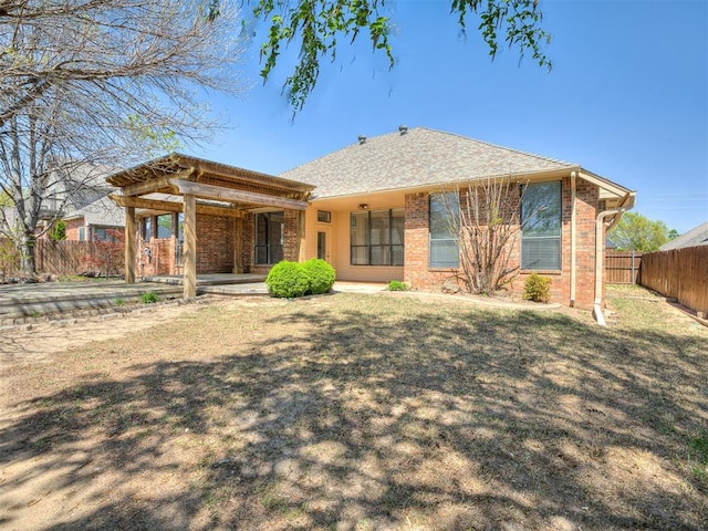back of property featuring brick siding, a lawn, and fence