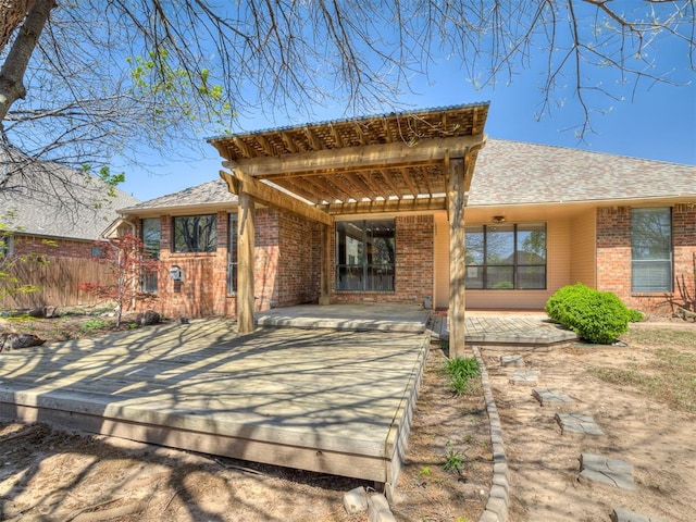 back of property with brick siding, fence, a patio, and a shingled roof