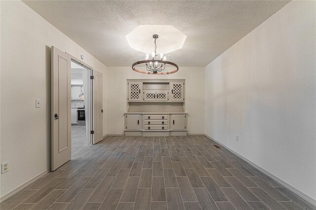 11800 Shasta Ln, Oklahoma City, OK 73162 - unfurnished room featuring baseboards, a textured ceiling, an inviting chandelier, and dark wood finished floors