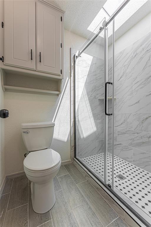 11800 Shasta Ln, Oklahoma City, OK 73162 - full bath featuring toilet, a shower stall, baseboards, and a textured ceiling