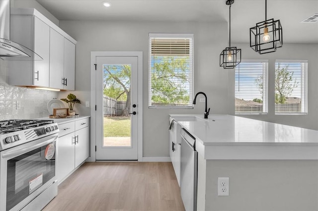 508 NW 175th St, Edmond, OK 73012 - kitchen featuring stainless steel appliances, wall chimney range hood, light countertops, a sink, and light wood-style flooring