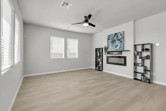 508 NW 175th St, Edmond, OK 73012 - unfurnished living room featuring a glass covered fireplace, plenty of natural light, and light wood-style floors