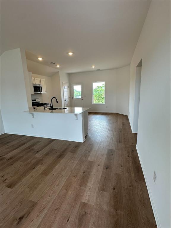 794 SW 11th St, Newcastle, OK 73065 - kitchen with appliances with stainless steel finishes, white cabinets, a sink, dark wood finished floors, and a peninsula