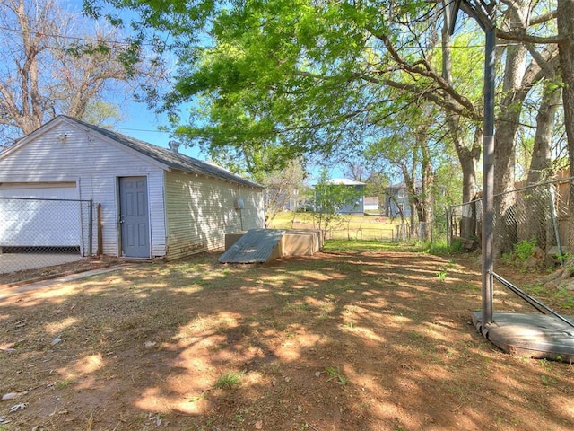 view of yard featuring a garage, an outdoor structure, and fence