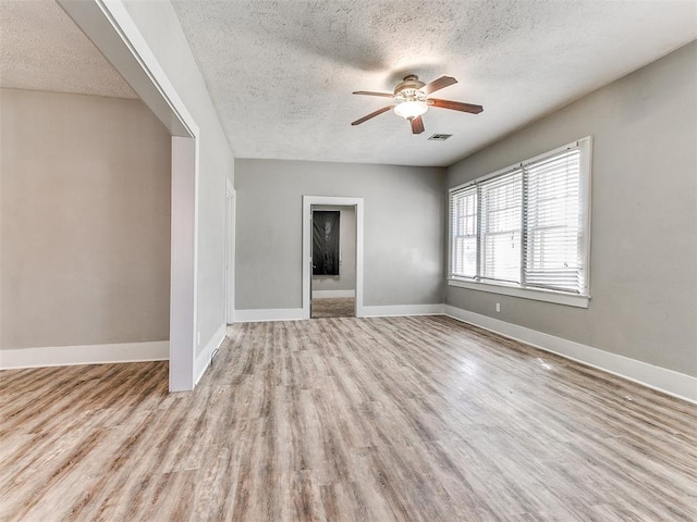 unfurnished living room featuring baseboards, a ceiling fan, wood finished floors, and a textured ceiling
