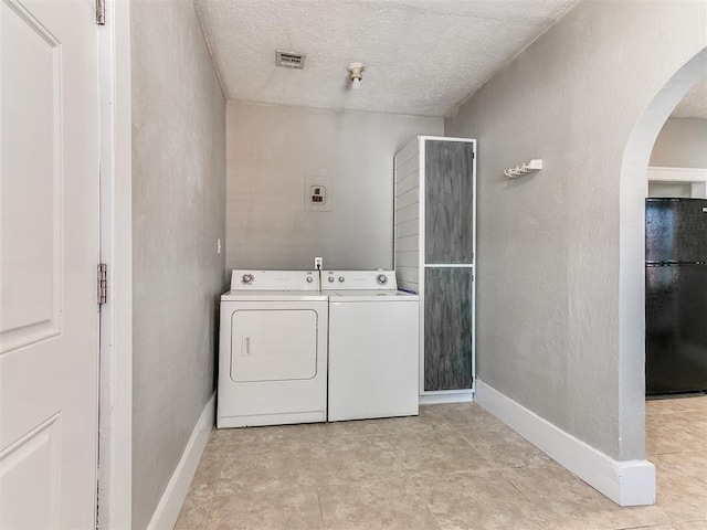 clothes washing area with visible vents, arched walkways, laundry area, a textured ceiling, and washing machine and dryer