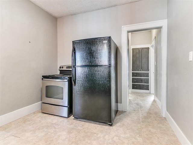 kitchen featuring baseboards, light tile patterned floors, a textured ceiling, freestanding refrigerator, and stainless steel electric stove