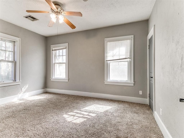 spare room with carpet flooring, visible vents, a textured ceiling, and ceiling fan
