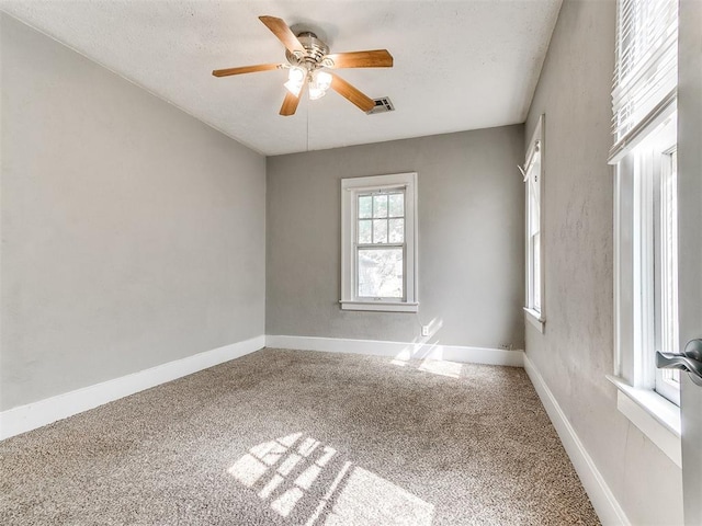 empty room with visible vents, ceiling fan, carpet floors, and baseboards