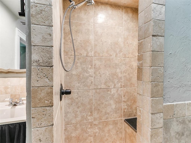 interior details featuring a sink and a tile shower