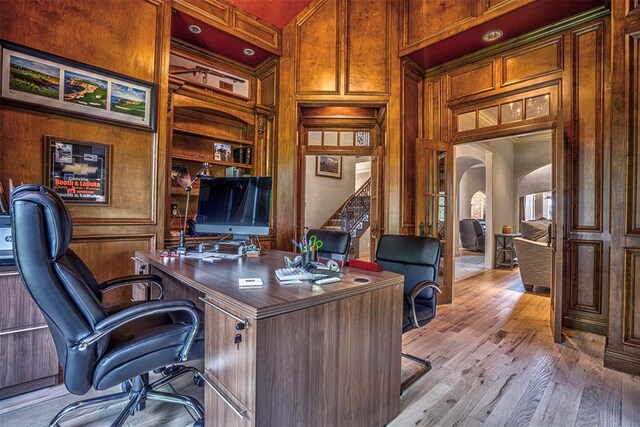 5100 Wisteria Dr, Oklahoma City, OK 73142 - home office with light wood-style floors, built in features, arched walkways, a towering ceiling, and wooden walls