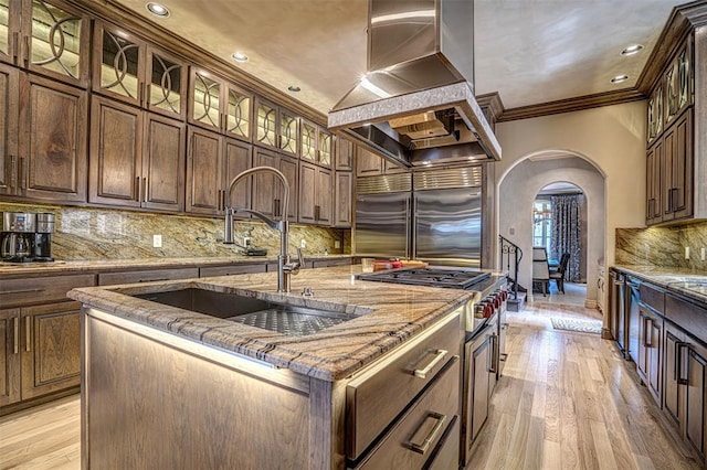 5100 Wisteria Dr, Oklahoma City, OK 73142 - kitchen with crown molding, arched walkways, wall chimney range hood, a sink, and stainless steel built in fridge