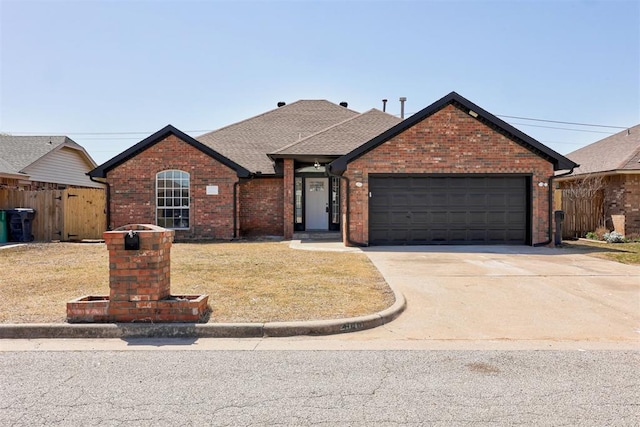 single story home with a front yard, a garage, driveway, brick siding, and fence