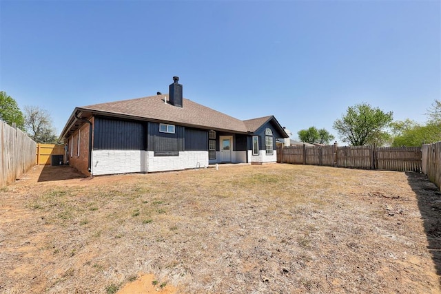 back of house featuring roof with shingles, a fenced backyard, and a chimney