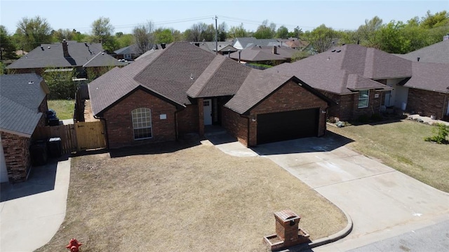 view of front facade with driveway, a gate, roof with shingles, fence, and brick siding