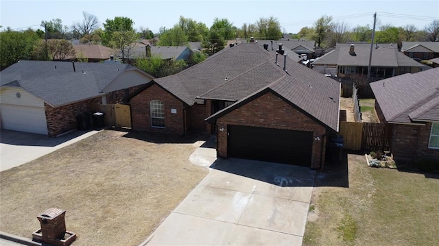 exterior space with concrete driveway, fence, an attached garage, and brick siding