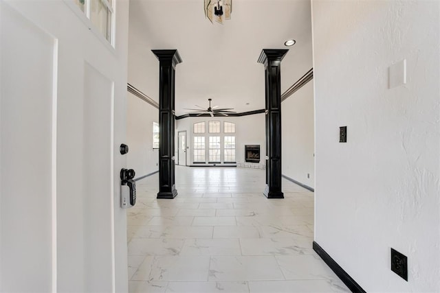 hallway with marble finish floor, baseboards, and ornate columns