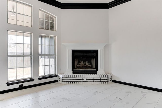 unfurnished living room with a fireplace with raised hearth, plenty of natural light, marble finish floor, and baseboards