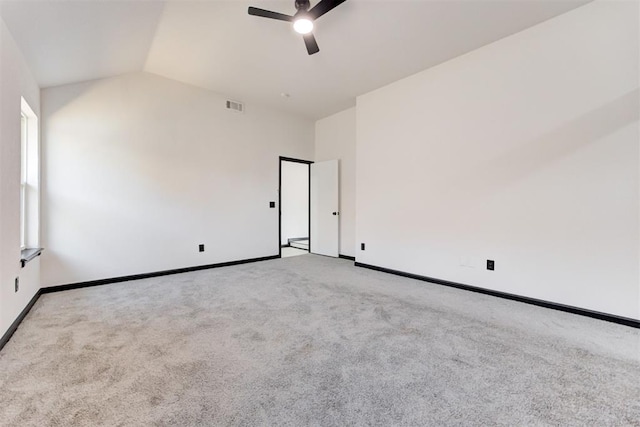 empty room featuring lofted ceiling, a ceiling fan, baseboards, and carpet floors