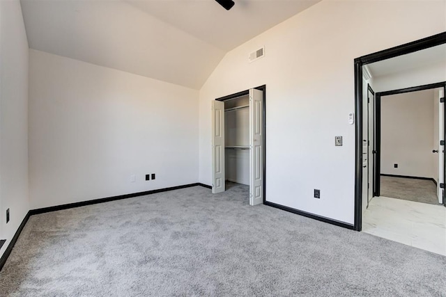 unfurnished bedroom with a closet, visible vents, light carpet, baseboards, and lofted ceiling