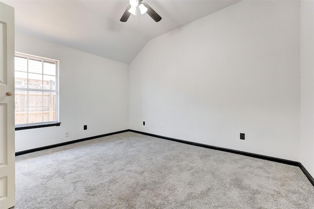 carpeted empty room with a ceiling fan, vaulted ceiling, and baseboards