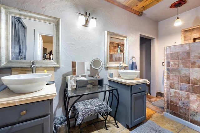 full bath featuring a textured wall, two vanities, and a sink