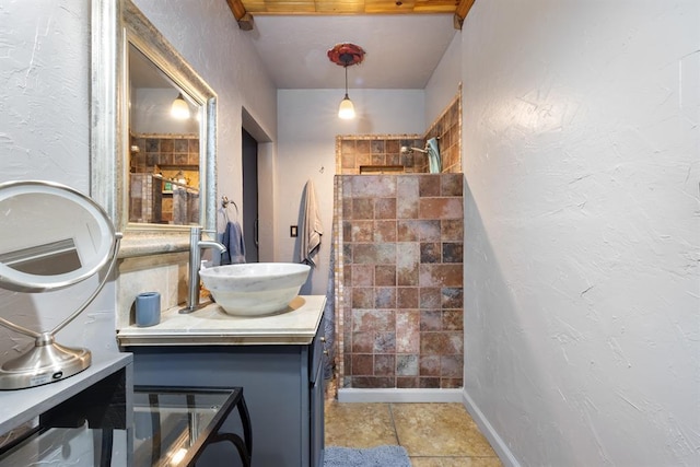 bathroom featuring a shower, vanity, and a textured wall