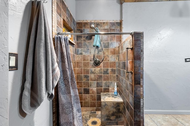 full bath featuring baseboards and tiled shower