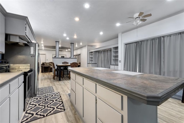 kitchen featuring ceiling fan, stainless steel electric stove, a kitchen island, and light wood-style floors