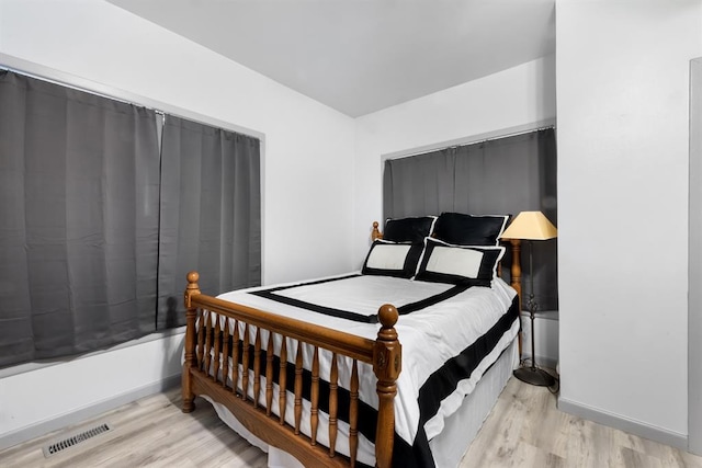 bedroom featuring visible vents, baseboards, and wood finished floors